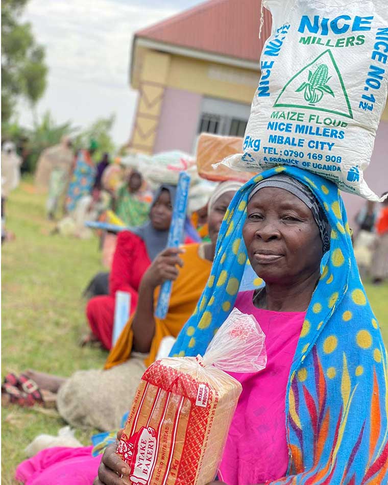Widow-seated-on-ground-with-a-bag-of-maize-floor-balancing-on-the-head-after-recieving-food-aid-in-Eastern-Uganda